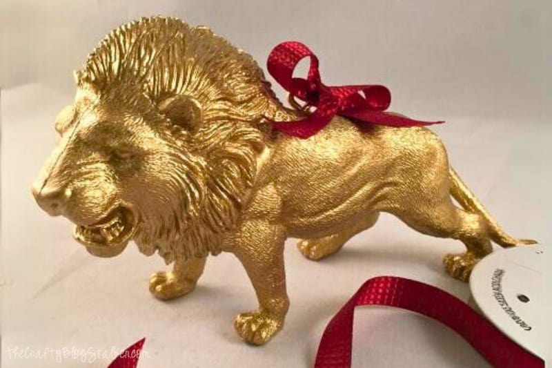 Gold painted lion with a red ribbon tied around the eye screw.
