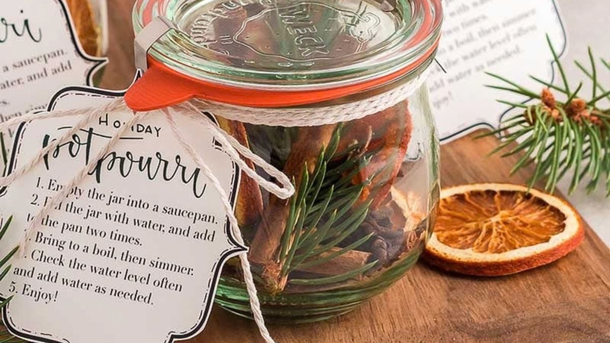 Stovetop potpourri gift jar filled with cinnamon sticks, pine sprigs, and dried fruit, tied with a holiday simmer pot instruction tag.