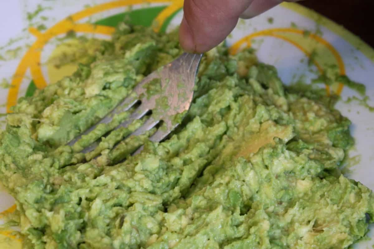 Mushing the avocado with a fork.
