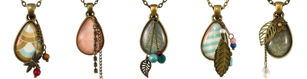 Five teardrop glass pendants on bronze chains, each decorated with patterned paper, beads, charms, and metal accents for unique handmade necklaces.
