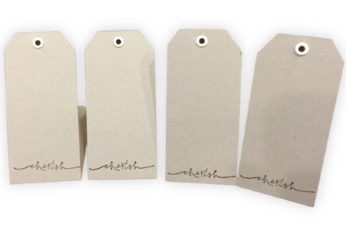 Four kraft paper tags with white eyelets, each stamped with the word "cherish" in elegant script, ready to be used for jewelry display or personalized gift tags.