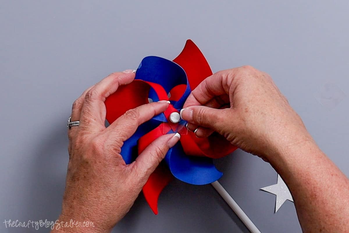 Placing a glue dot on the front of the pinwheel.
