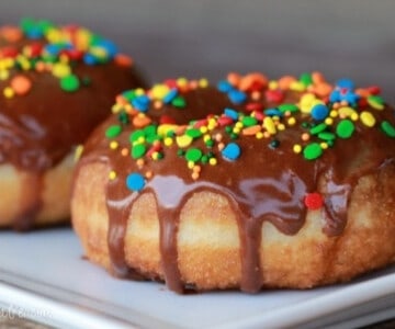 Chocolate glazed donuts on a white plate.