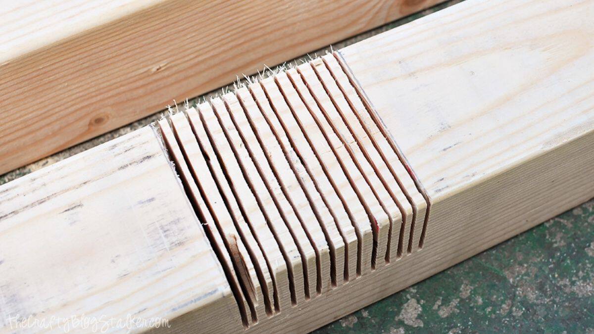 Close-up of a wooden board with multiple saw cuts for creating a lap joint during a DIY farmhouse table woodworking project.
