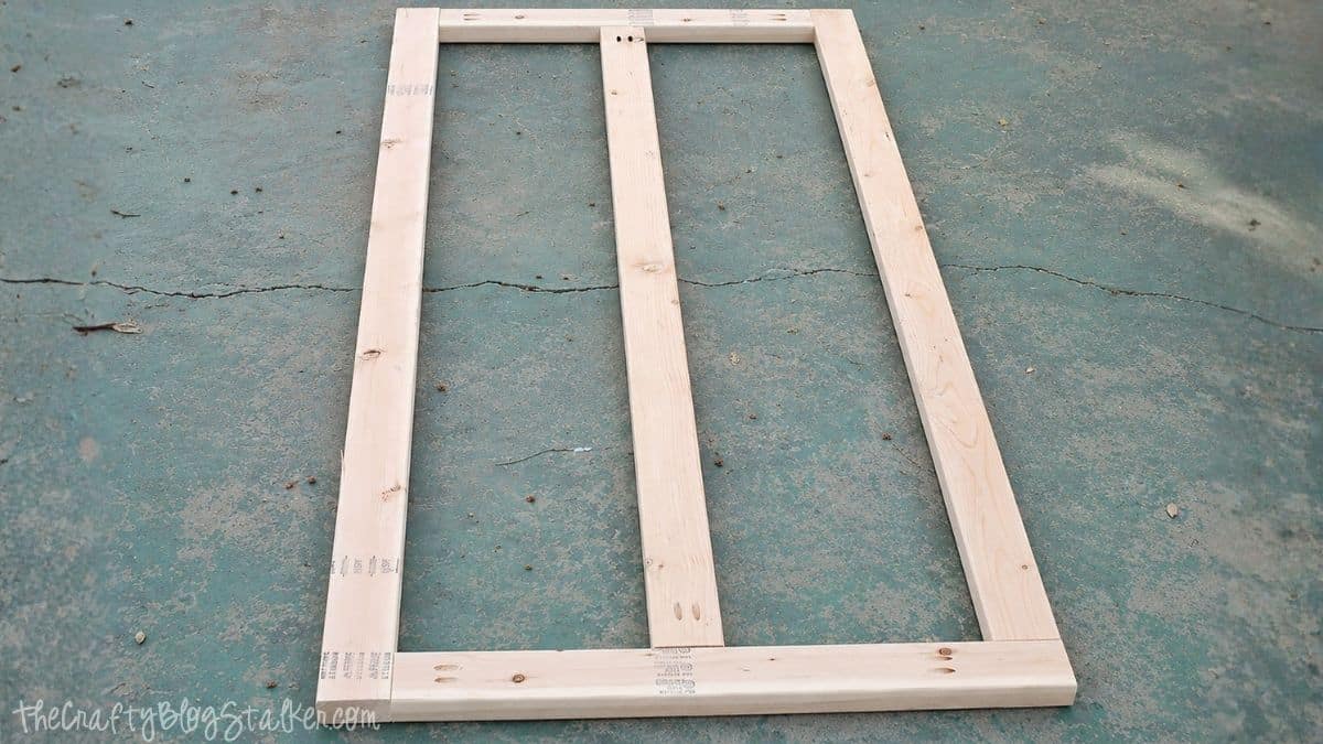 Rectangular wooden frame with center support assembled on a concrete surface for a DIY farmhouse table project.