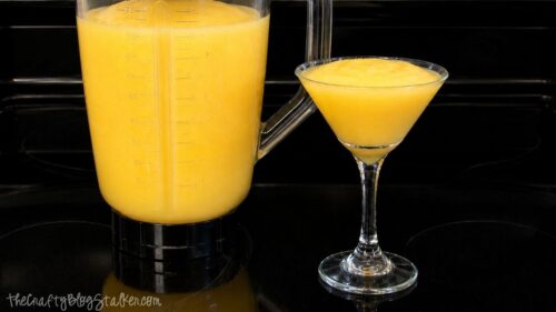 Homemade orange juice slushie blended until smooth, shown in a blender pitcher and served in a glass.