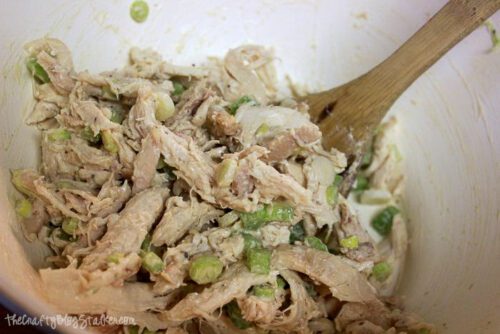 chicken salad in a white bowl with a wooden spoon