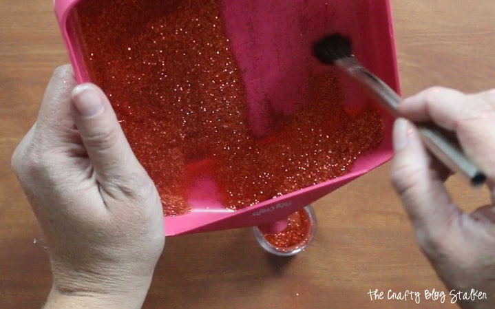 putting glitter back in the bottle with a craft tray and brush