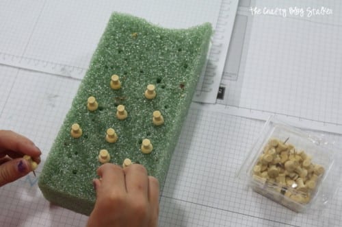 image of sticking wood pins into a foam block getting them ready to paint