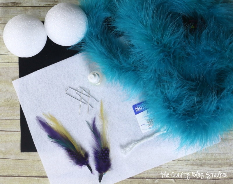 Blue feather boa, to styrofoam balls, peacock feathers, felt, and floral pins.