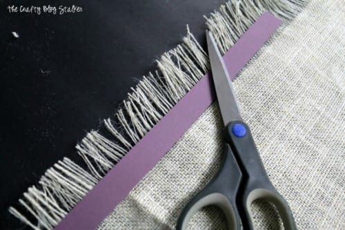 cutting the fringe on your burlap table runner with a pair of scissors and paper guide