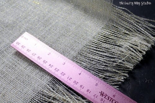 measuring the length of fringed trim on a burlap table runner