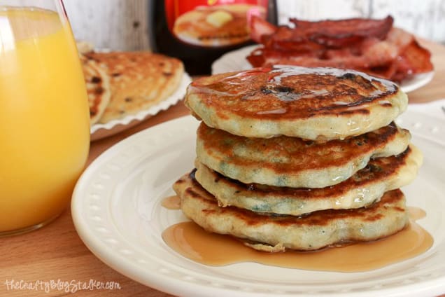 a stack of blueberry pancakes on a white plate