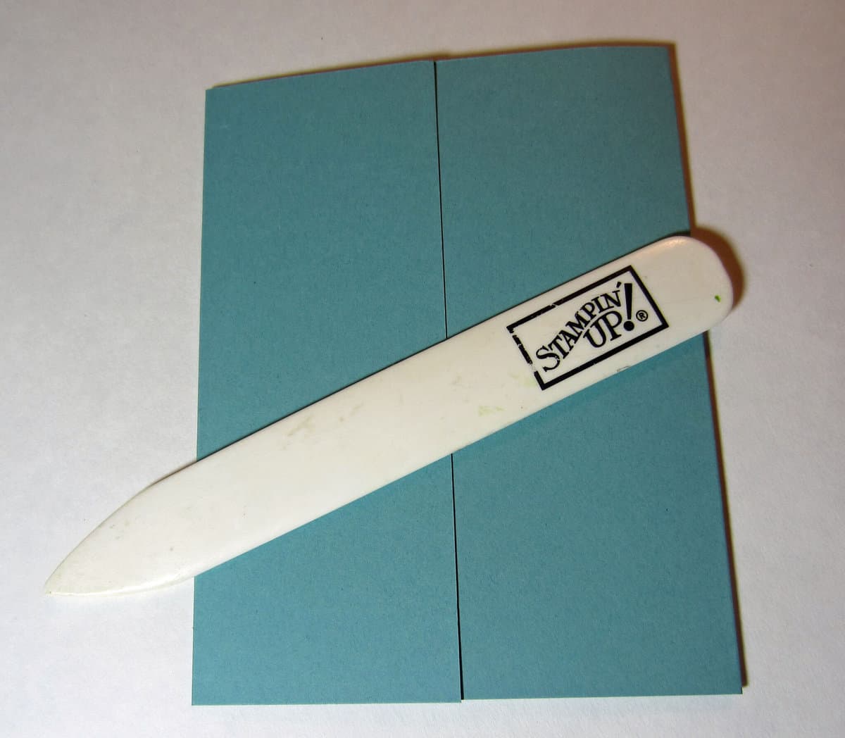 a white bone folder on a folded card