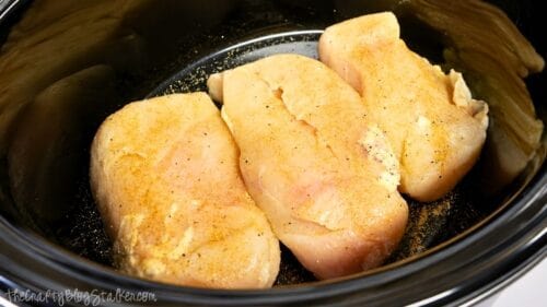 Raw chicken breasts seasoned with spices in a slow cooker, ready to cook for Hawaiian haystacks or shredded chicken recipes.