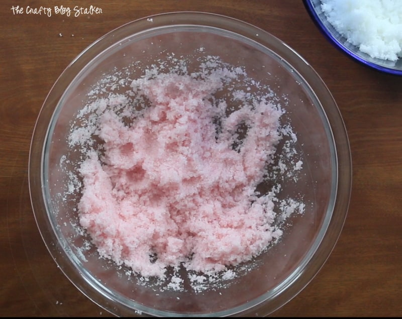 adding red food coloring to a bowl of sugar scrub