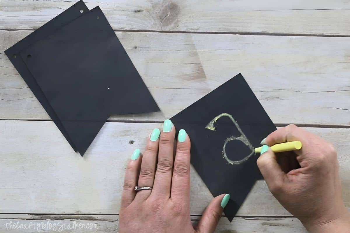 Writing the letter a on a chalkboard banner flag.