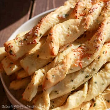 A white plate filled with Garlic Parmesan Breadsticks.