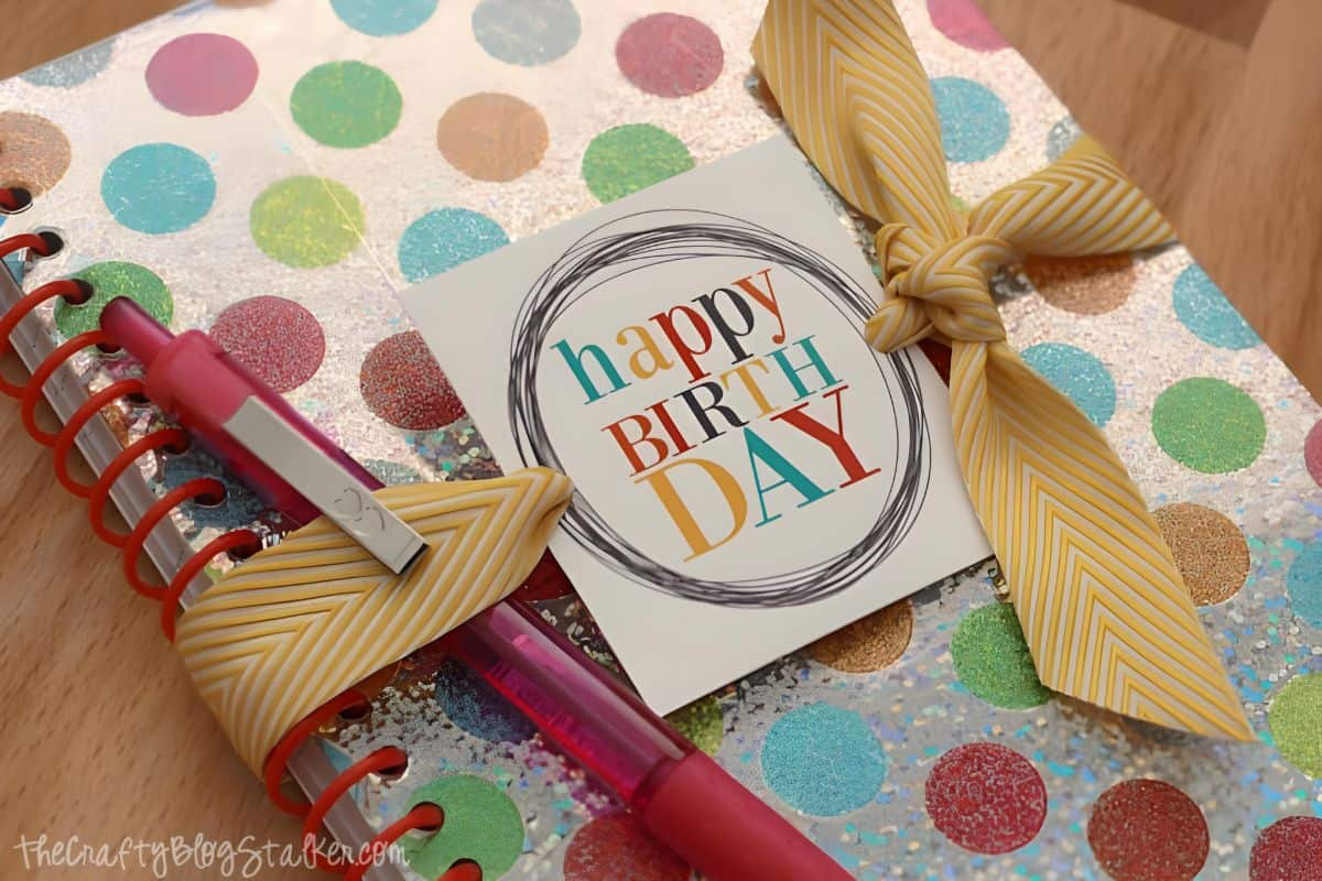 Happy Birthday Gift Tag tied to a notebook with yellow ribbon.