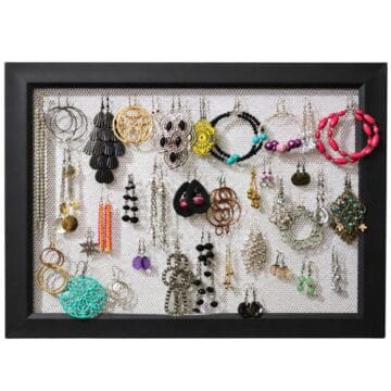 Black frame with metal mesh backing displaying a variety of hanging earrings organized by style and size.