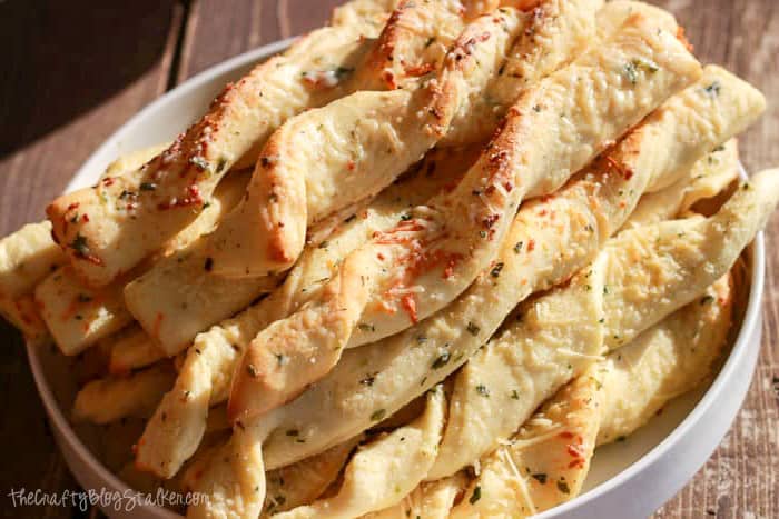 A white plate filled with Garlic Parmesan Breadsticks.
