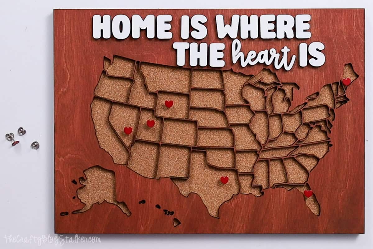 Completed 'Home Is Where The Heart Is' sign with pins marking where family lives in the US.