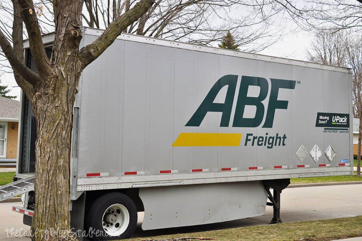 Parked ABF Freight moving truck with U-Pack logo on a suburban street, ramp extended for loading or unloading.