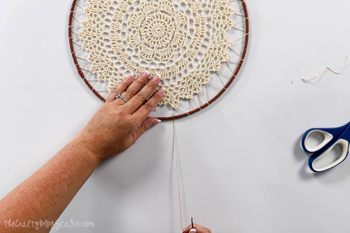 lacing the doily to the ring with twine