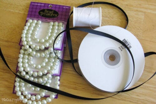 pearls, black ribbon, sewing thread and a needle