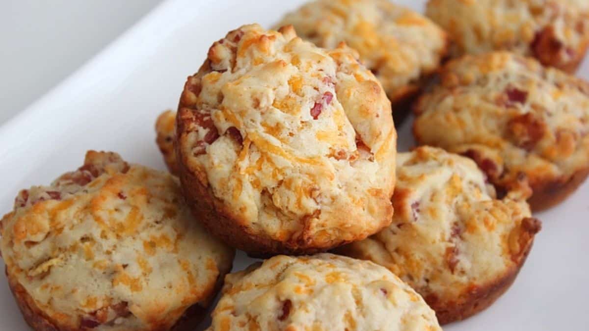 A close-up view of freshly baked bacon cheddar muffins arranged on a white plate.