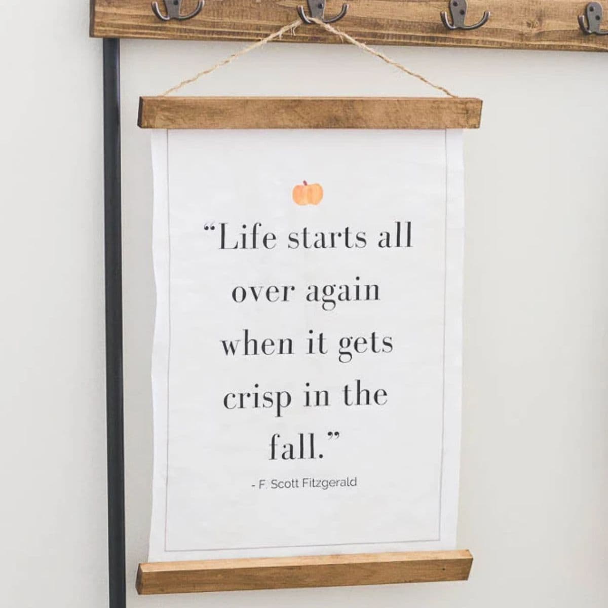 Fall quote printable with a small pumpkin, displayed in a rustic wooden hanging frame with the F. Scott Fitzgerald quote about crisp fall weather.