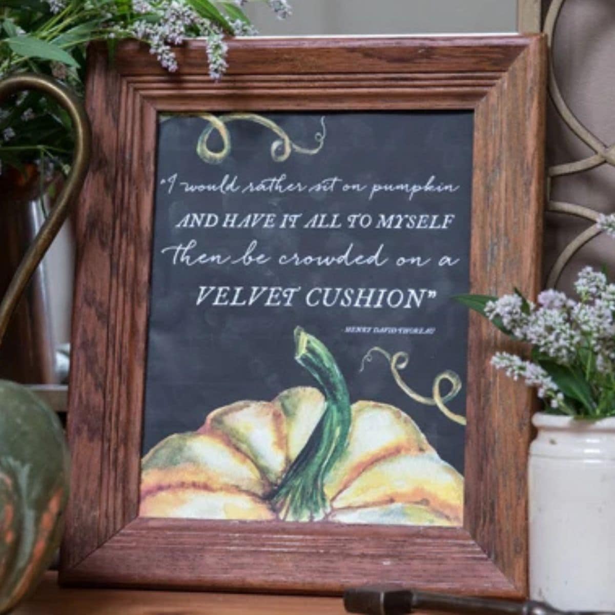 Framed fall pumpkin printable with a chalkboard background, watercolor pumpkin, and Mary Engelbreit quote, styled with greenery and flowers.