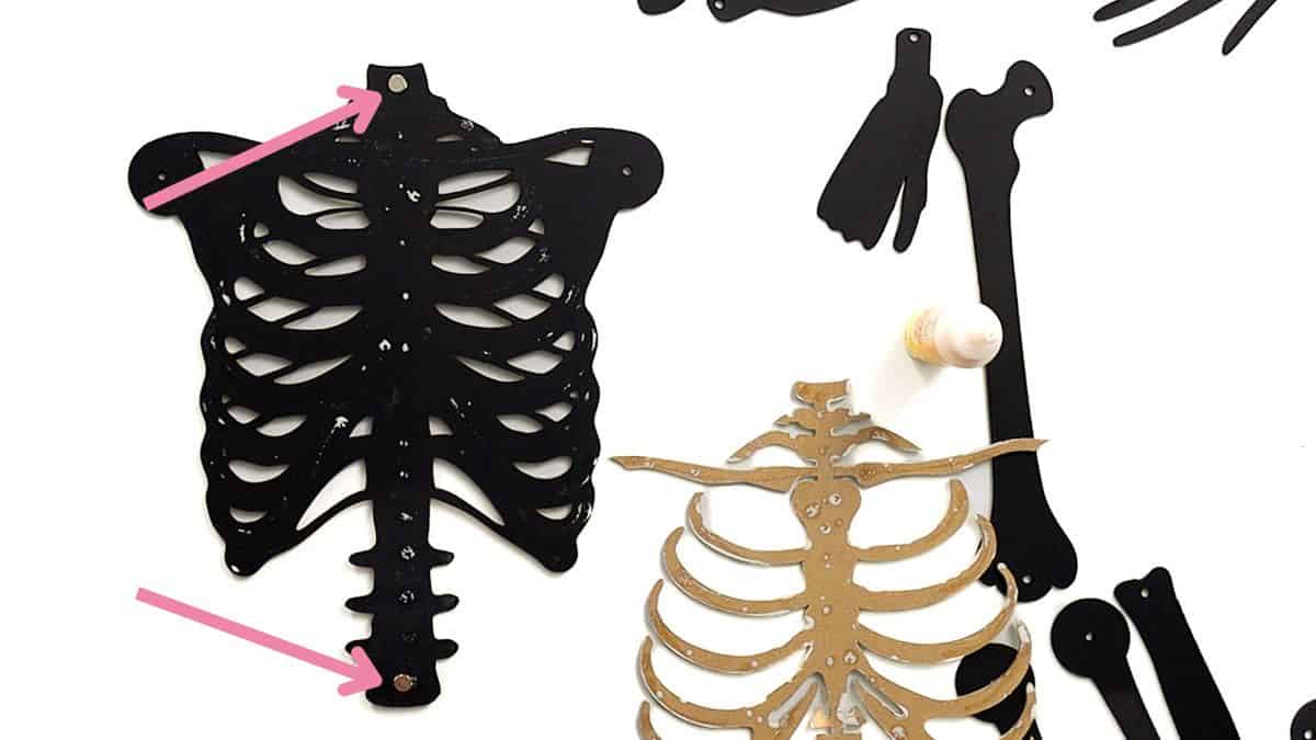 Black painted laser cut skeleton chest with screw casings inserted, shown alongside unpainted ribcage and other black skeleton pieces.
