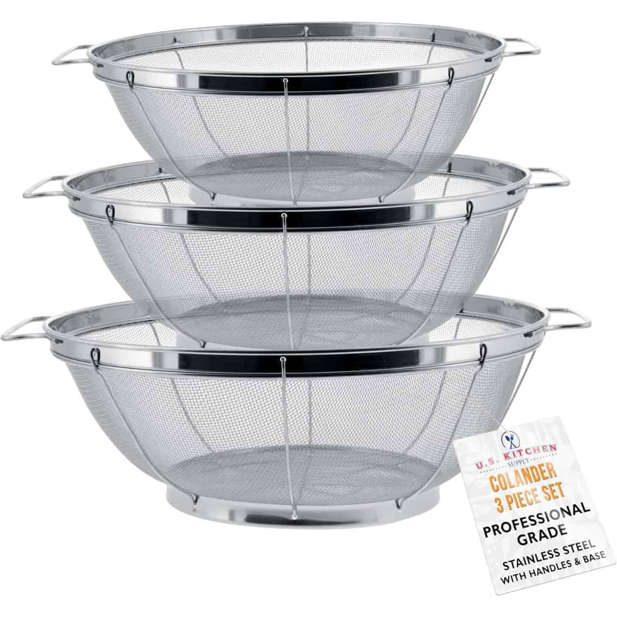 A stack of three stainless steel mesh colanders with handles and bases, labeled as a professional-grade 3-piece set from U.S. Kitchen Supply.