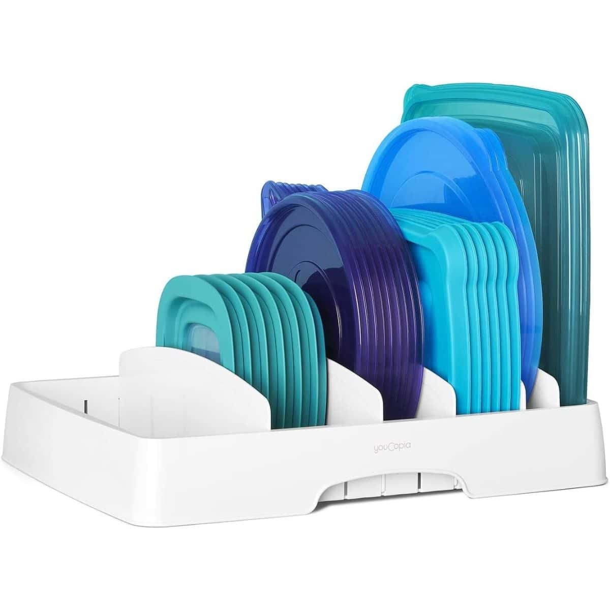 A white plastic container lid organizer neatly holding blue, teal, and purple food storage lids of various shapes and sizes.