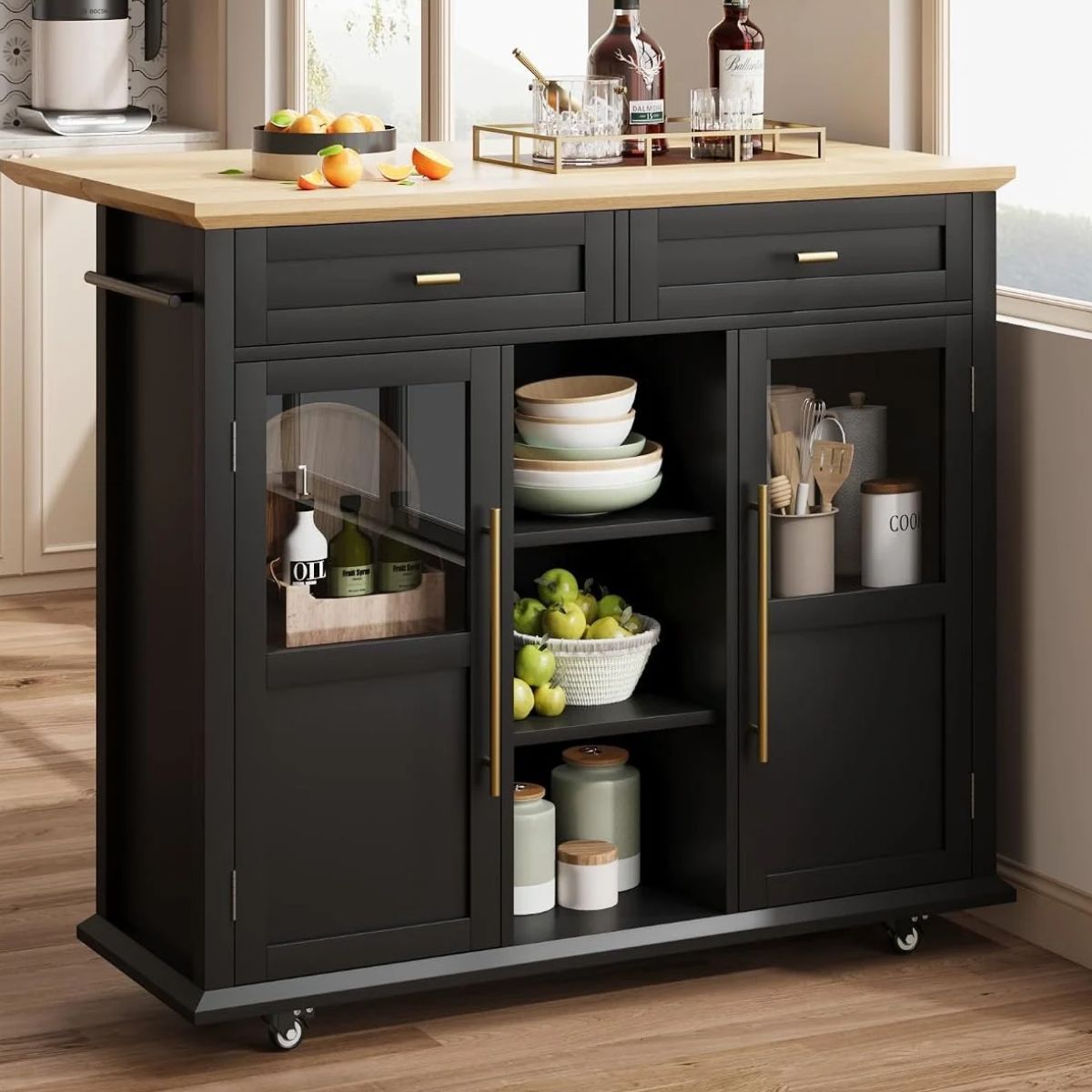 A blue kitchen island with wooden countertop, built-in storage shelves, drawers, and stools, styled with wine bottles, jars, and a toaster.