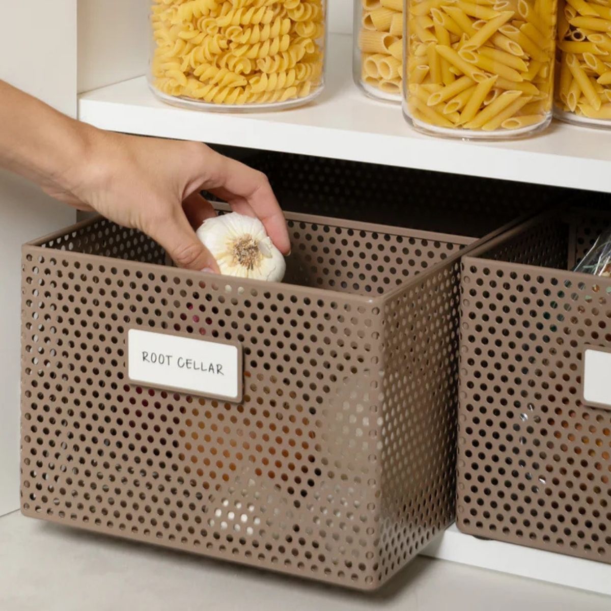 Hand reaching into a perforated metal pantry basket labeled