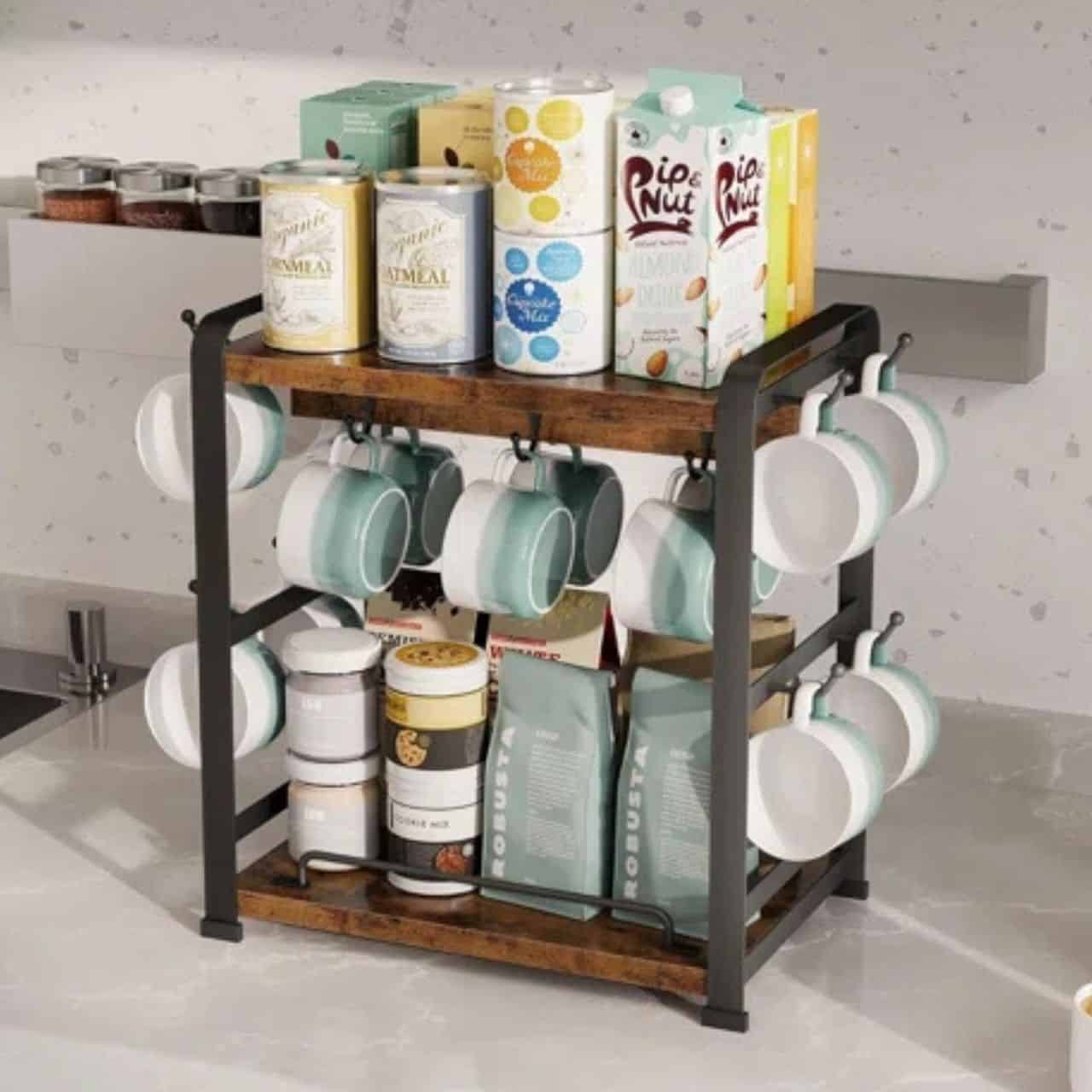 Two-tier coffee mug holder stand with hanging cups, coffee supplies, and drink cartons on a kitchen countertop.