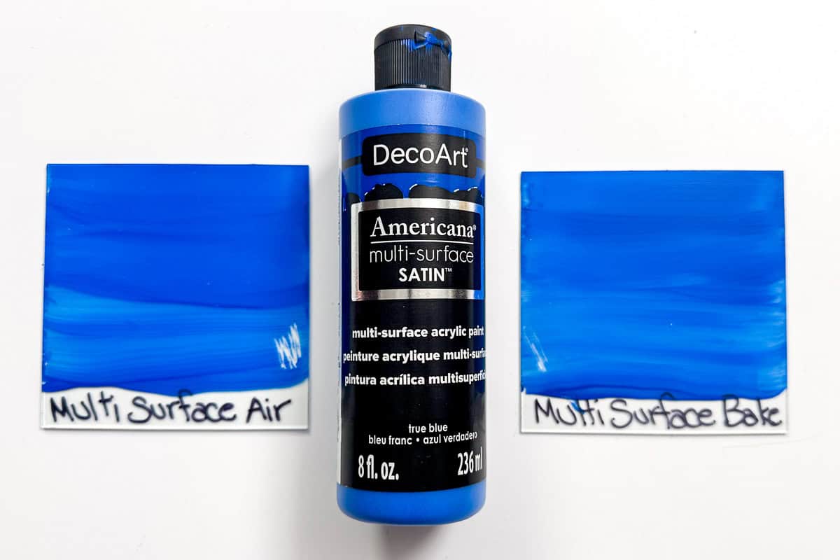 A bottle of Deco Art blue multi-surface satin paint next to 2 glass panes painted with the same paint.