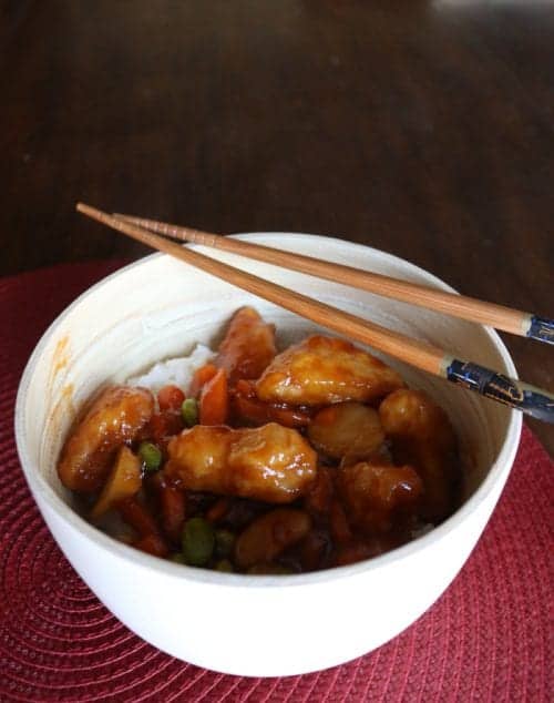 a white bowl of P.F. Chang's Home Menu orange chicken with a pair of chopsticks laying across the top of the bowl 