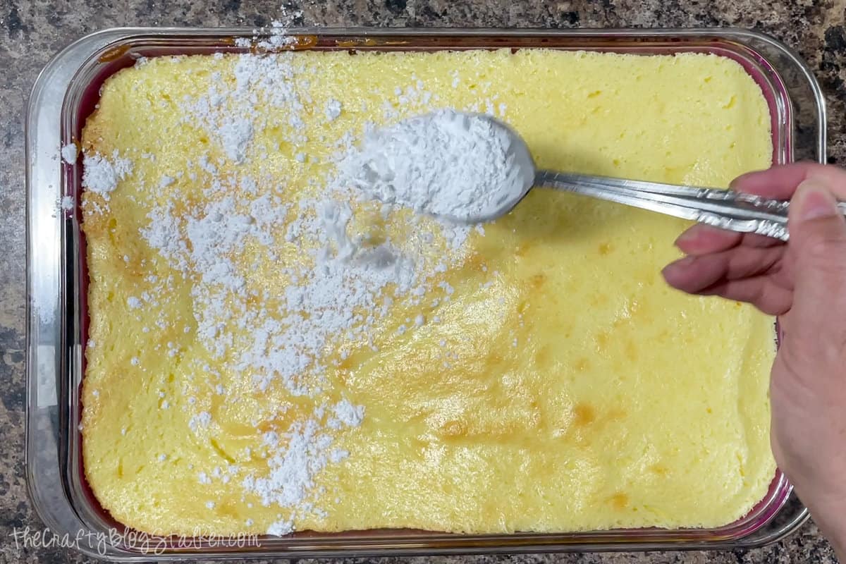 Sprinkling powdered sugar onto freshly baked lemon bars.