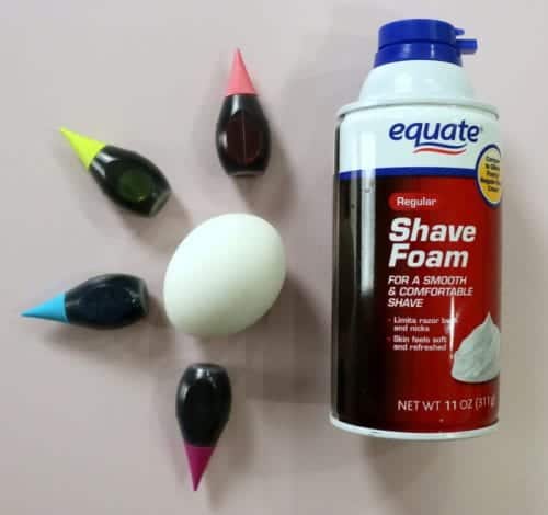 1 hard boiled egg with pink, yellow, blue, purple food coloring bottles and a can of shaving cream
