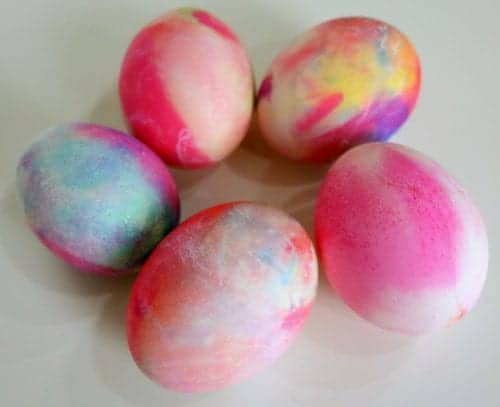 five hard boiled eggs that have been dyed in shaving cream and food coloring forming a circle