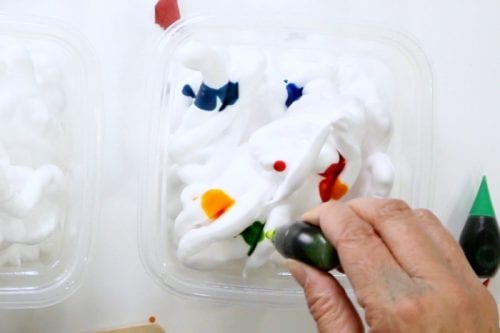 add drops of food coloring to containers filled with shaving cream