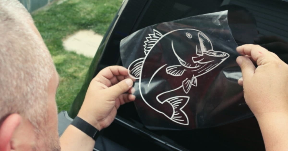 Applying a fish decal to a card back window.