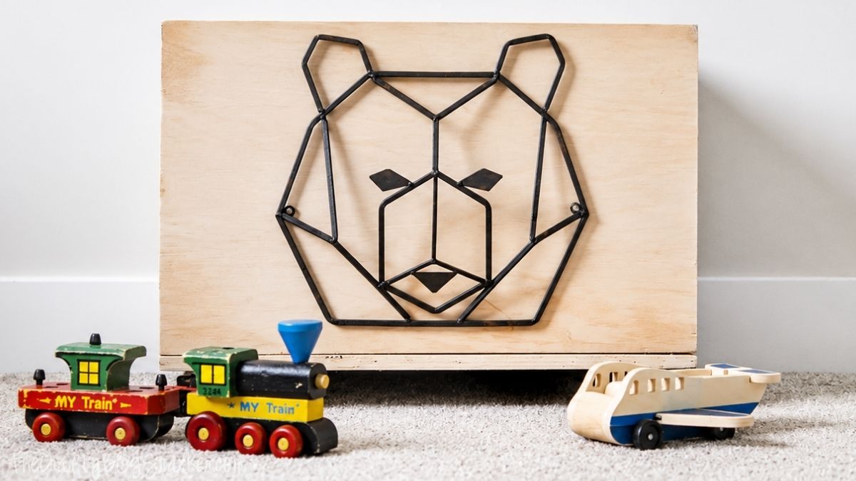 Wooden rolling toy box with a geometric bear design on the front, displayed with toy trains and a wooden airplane on carpet.