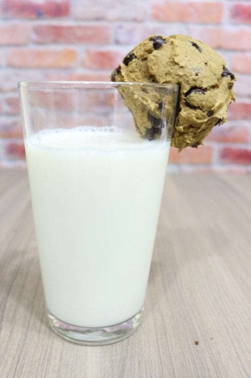 a pumpkin chocolate chip cookie on the side of a glass of milk