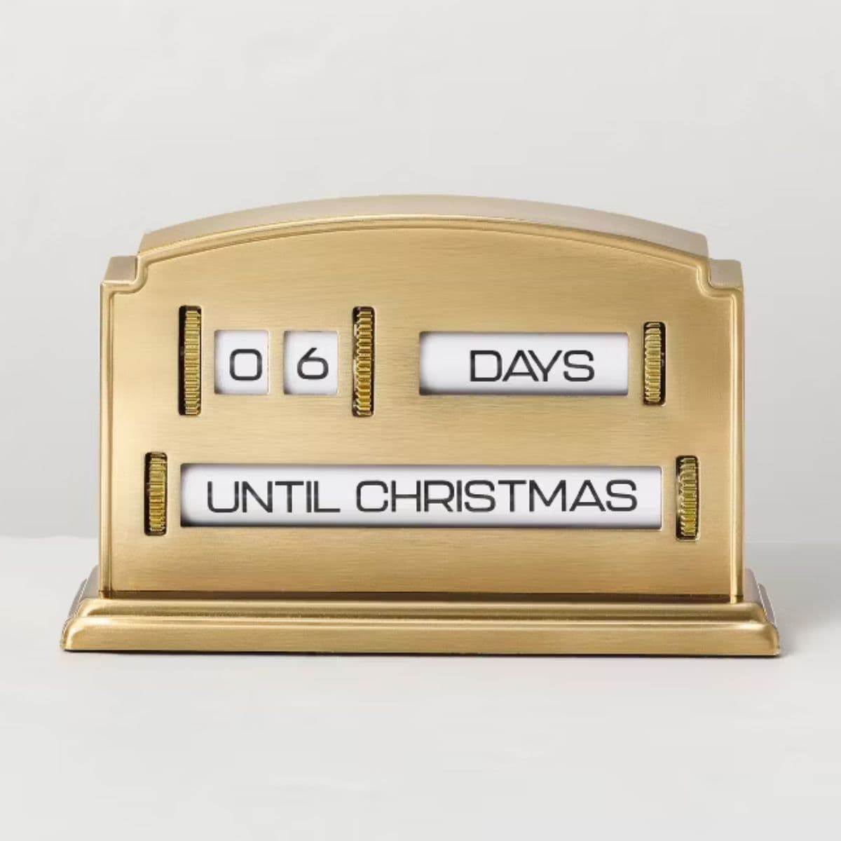 Gold metal flip-style advent calendar with black text displaying