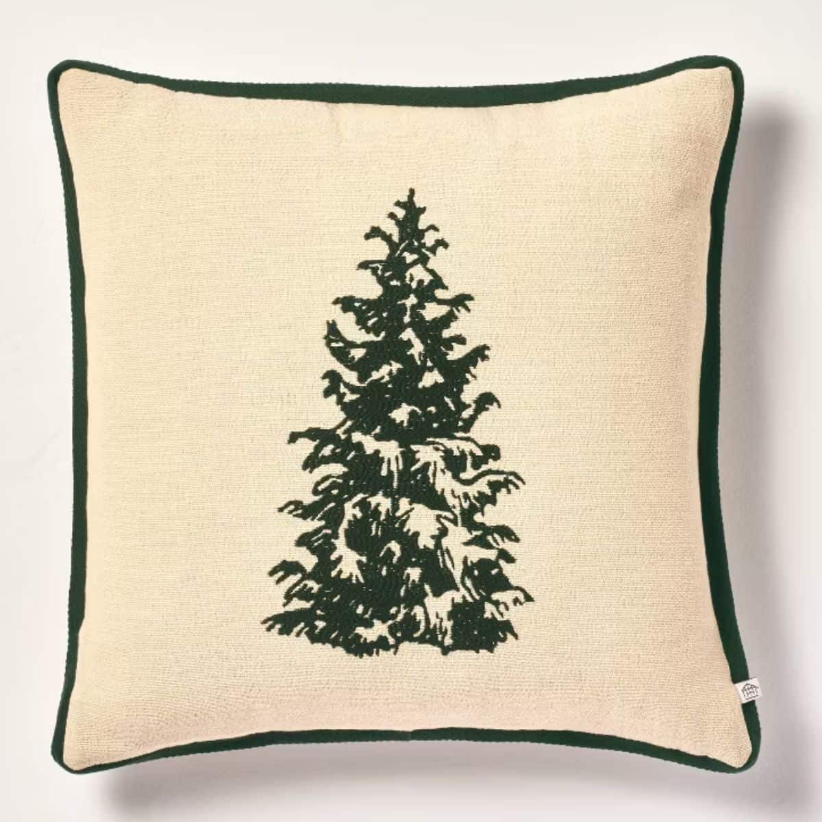 Cream-colored Christmas throw pillow with a dark green evergreen tree design and matching green piping around the edges.