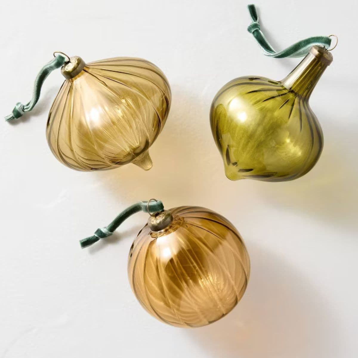 Set of three ribbed glass Christmas ornaments in amber and olive tones, each with a green velvet ribbon for hanging.